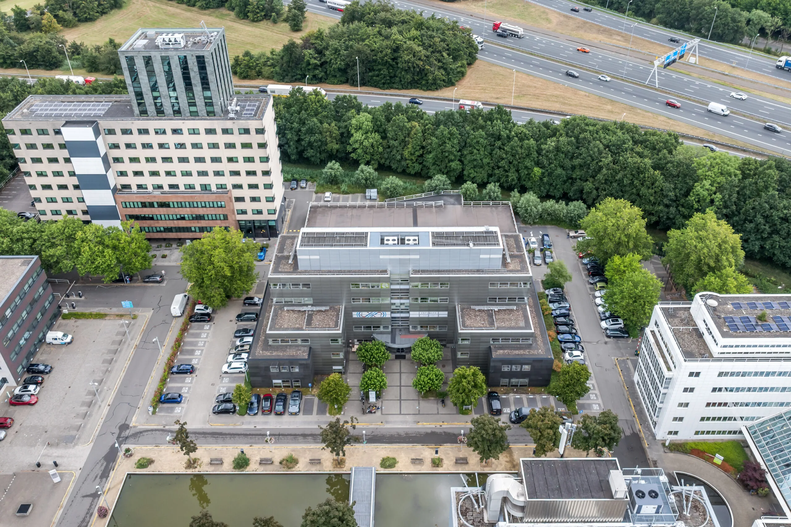 Luchtfoto van kantoorgebouw aan de Daltonlaan in Utrecht, omgeven door andere kantoren, parkeerplaatsen en een snelweg op de achtergrond.