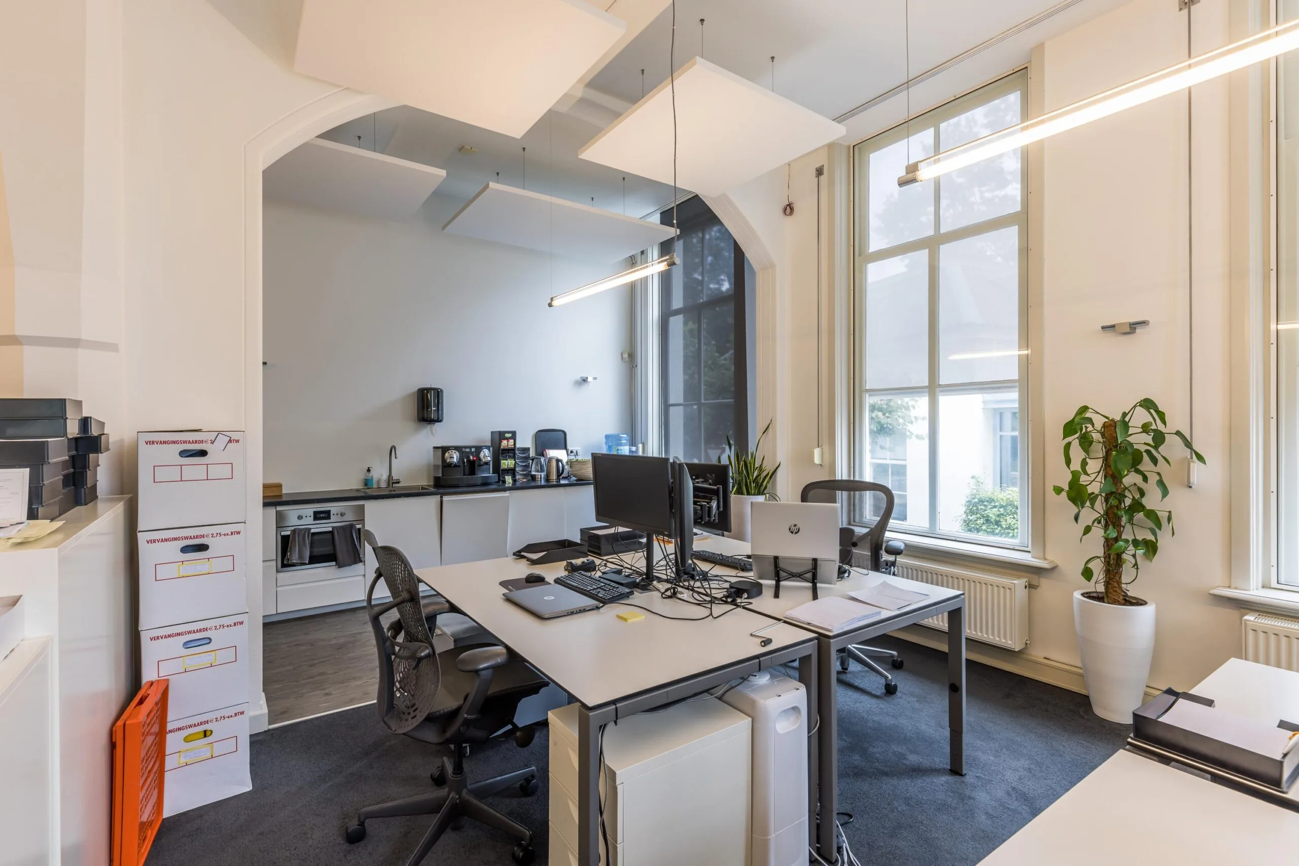 Modern ingericht kantoor aan de Driebergseweg met werkplekken, grote ramen en een kitchenette.