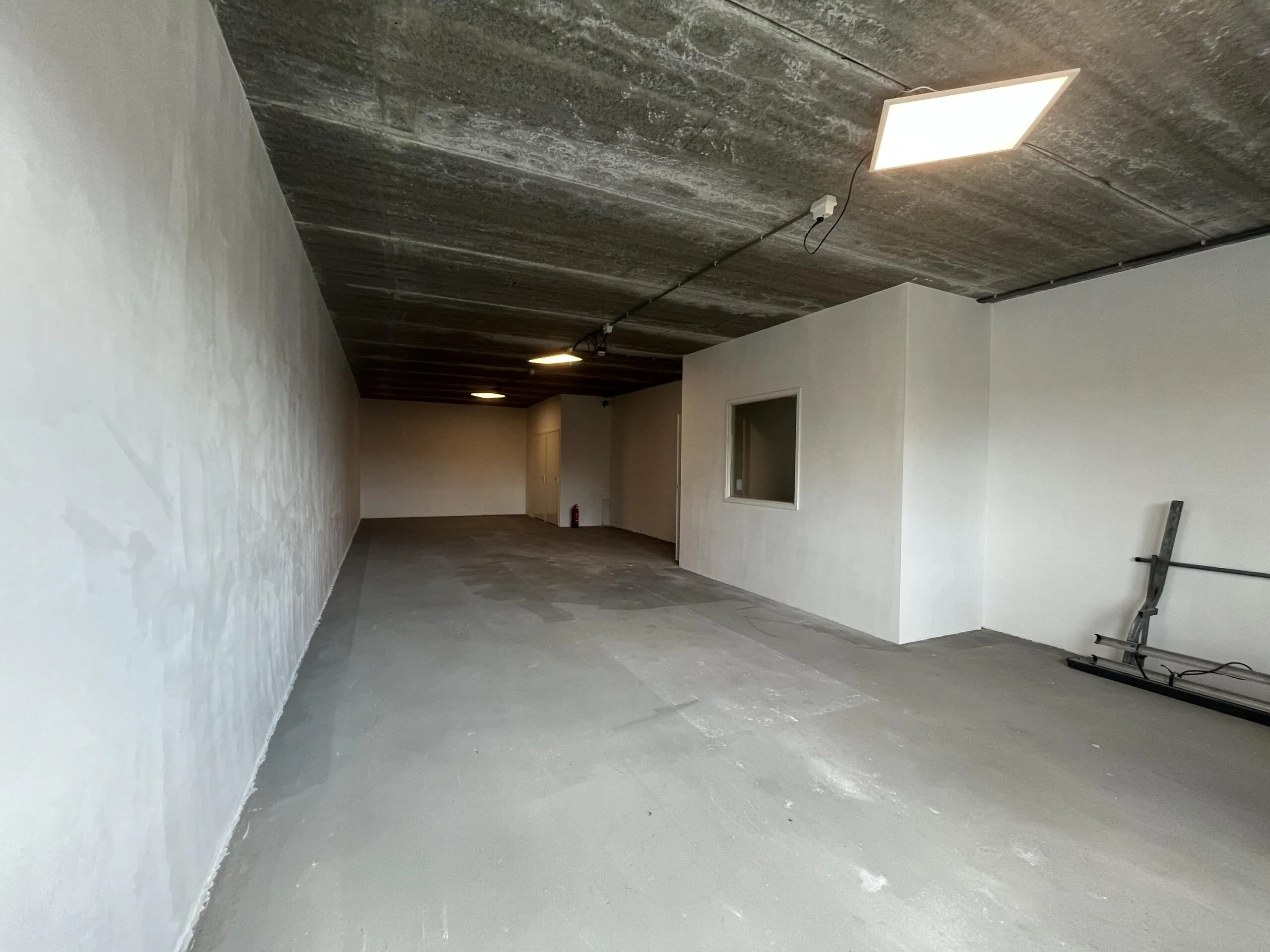 Een lege, kale ruimte met betonvloer en witte muren op Broekdijk West.