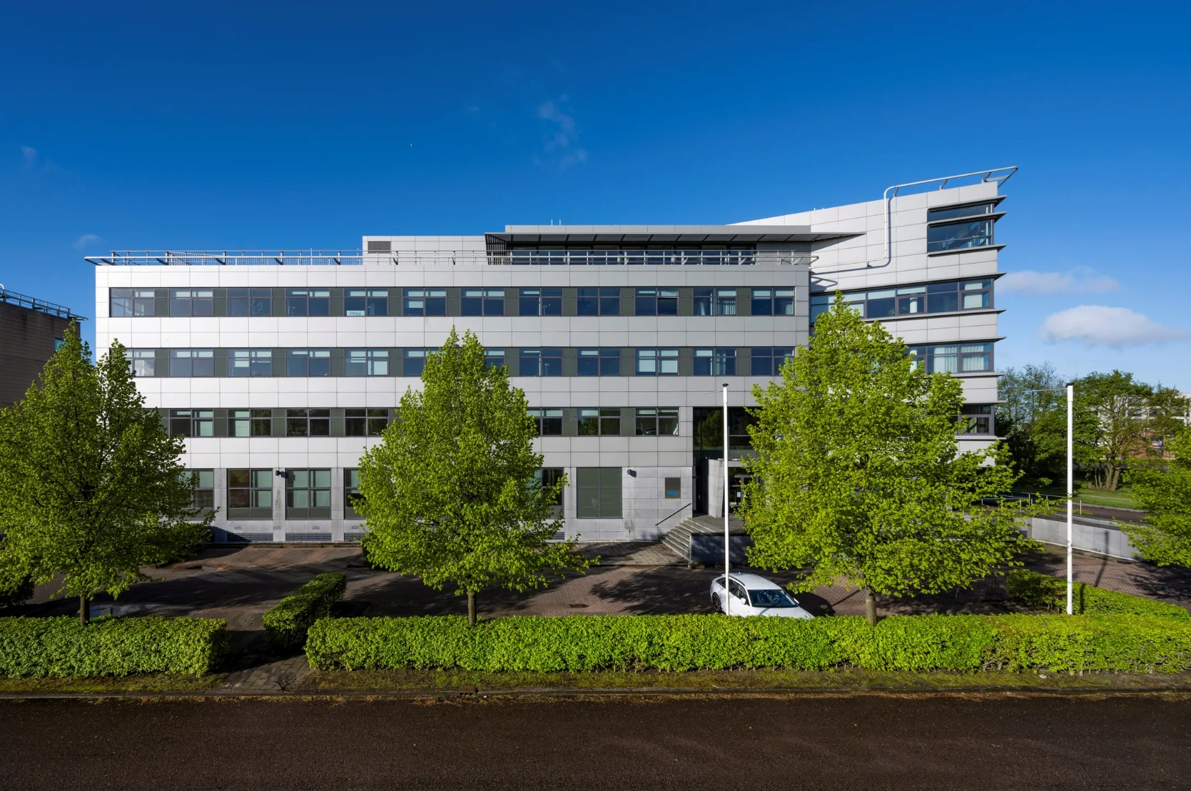 Modern kantoorgebouw aan de Boeingavenue met glazen gevel en omliggende groenvoorziening.