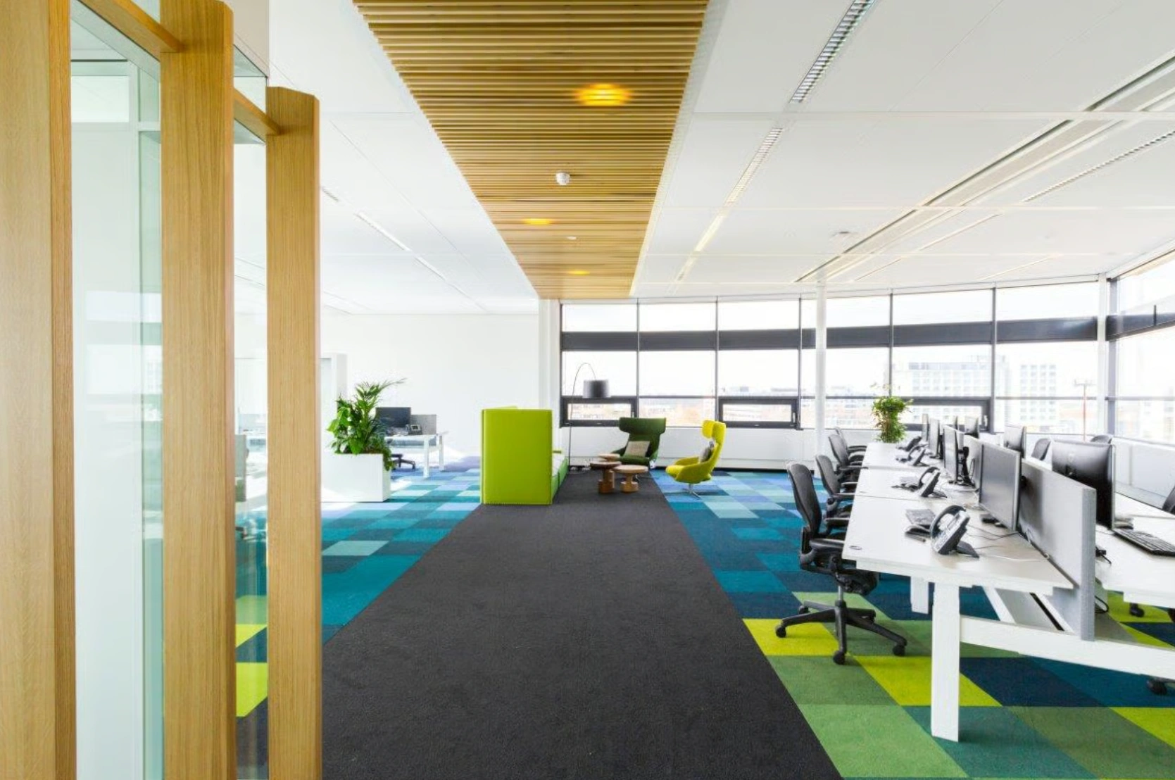 Modern en licht kantoorinterieur aan de Boeing Avenue met flexwerkplekken, kleurrijke vloerbedekking en loungehoek.