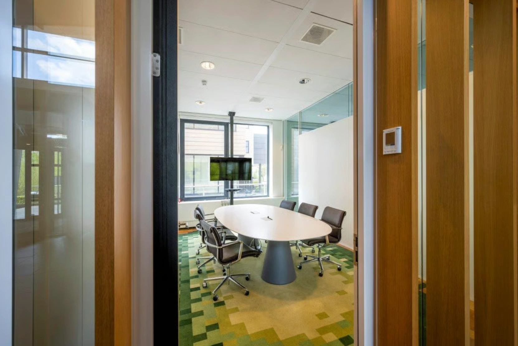 Vergaderruimte op Boeing Avenue met ovale tafel, zes stoelen en een flatscreen aan het raam.
