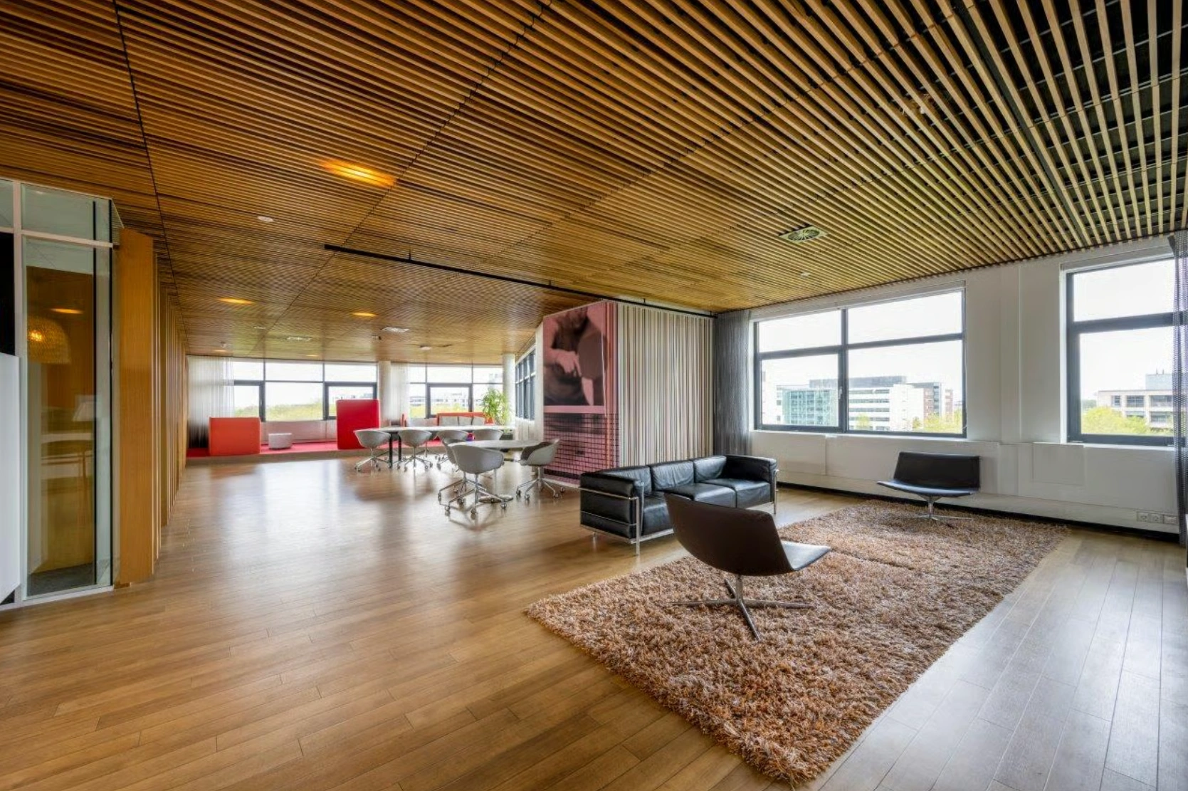 Modern ingericht kantoor op Boeing Avenue met houten vloer, designmeubilair en grote ramen met uitzicht op omliggende gebouwen.