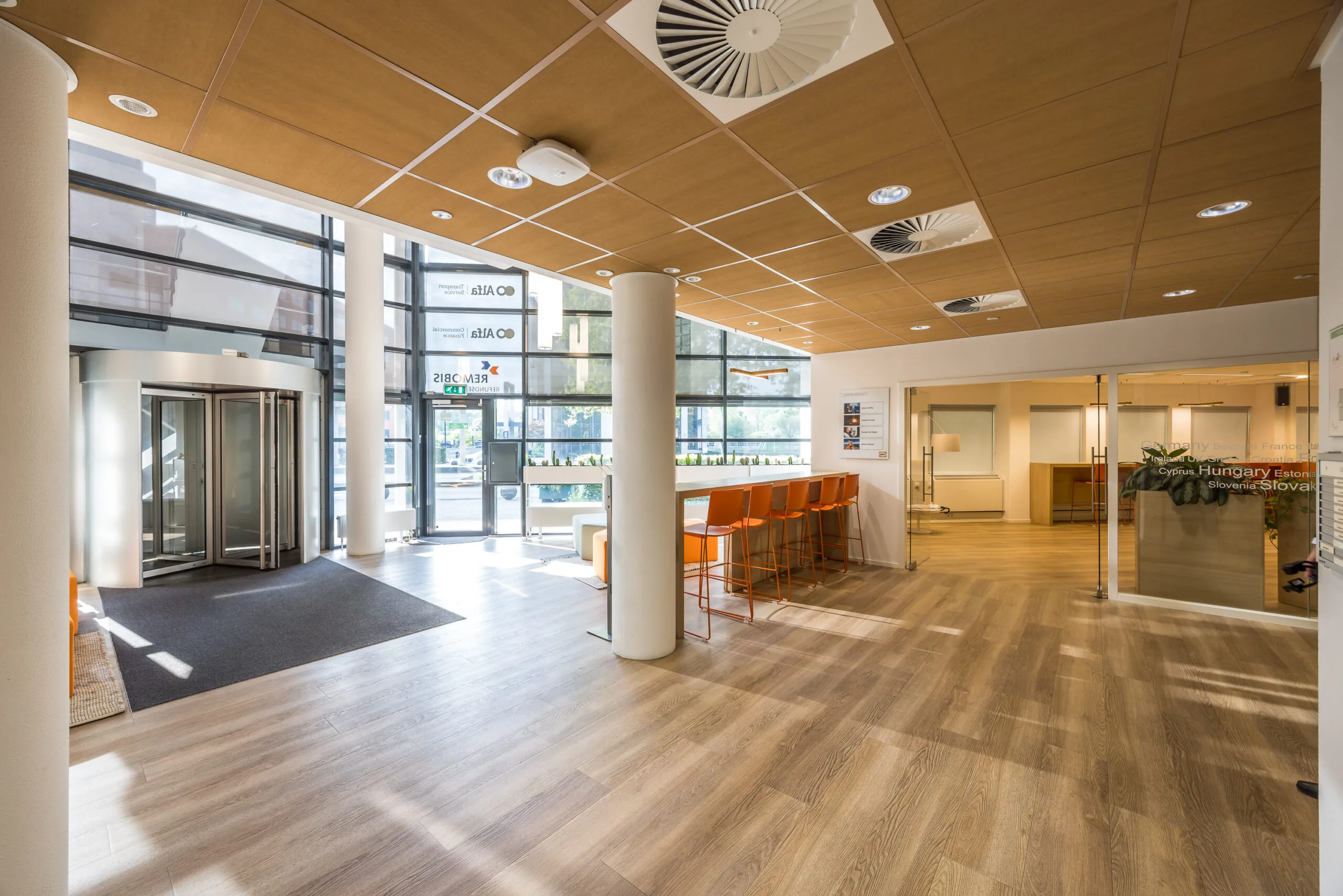 Moderne en lichte entreehal van een kantoorpand aan de Varrolaan met zitgedeelte en glazen deuren.
