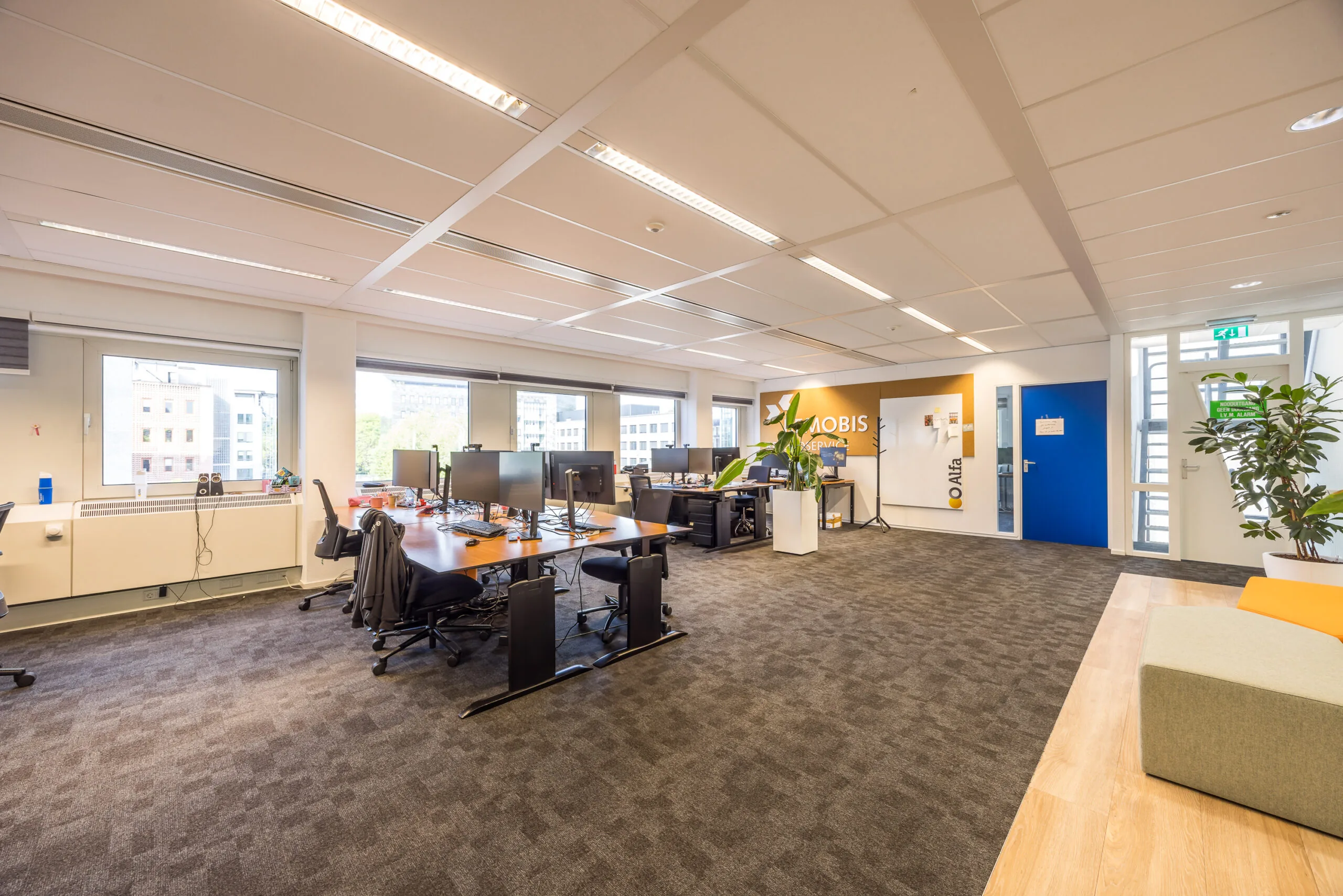 Moderne en open kantoorruimte van Mobis aan de Varrolaan met bureaus, computerschermen en een ontvangstgedeelte.