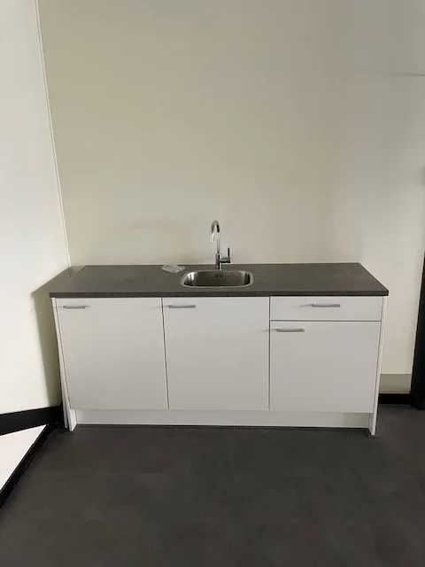Witte kitchenette met een grijs aanrechtblad en een rvs-kraan aan de Laan van s-Gravenmade.