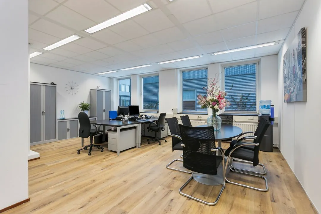 Moderne kantoorruimte aan de Hoefsmidstraat met bureaus, vergadertafel, bloemenvaas en watercooler.