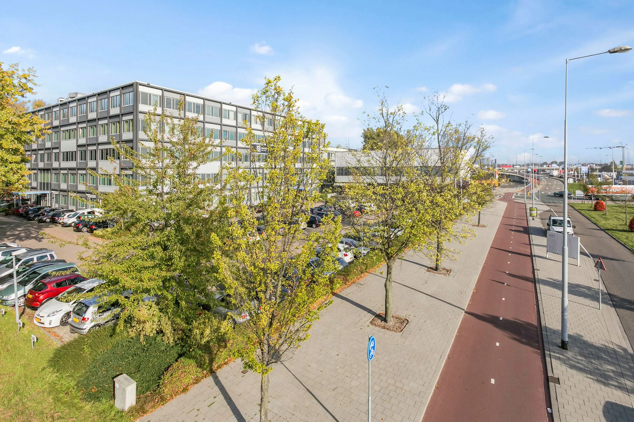 Kantoorgebouw aan de Hoefsmidstraat met aangrenzende parkeerplaats en naastgelegen fietspad.