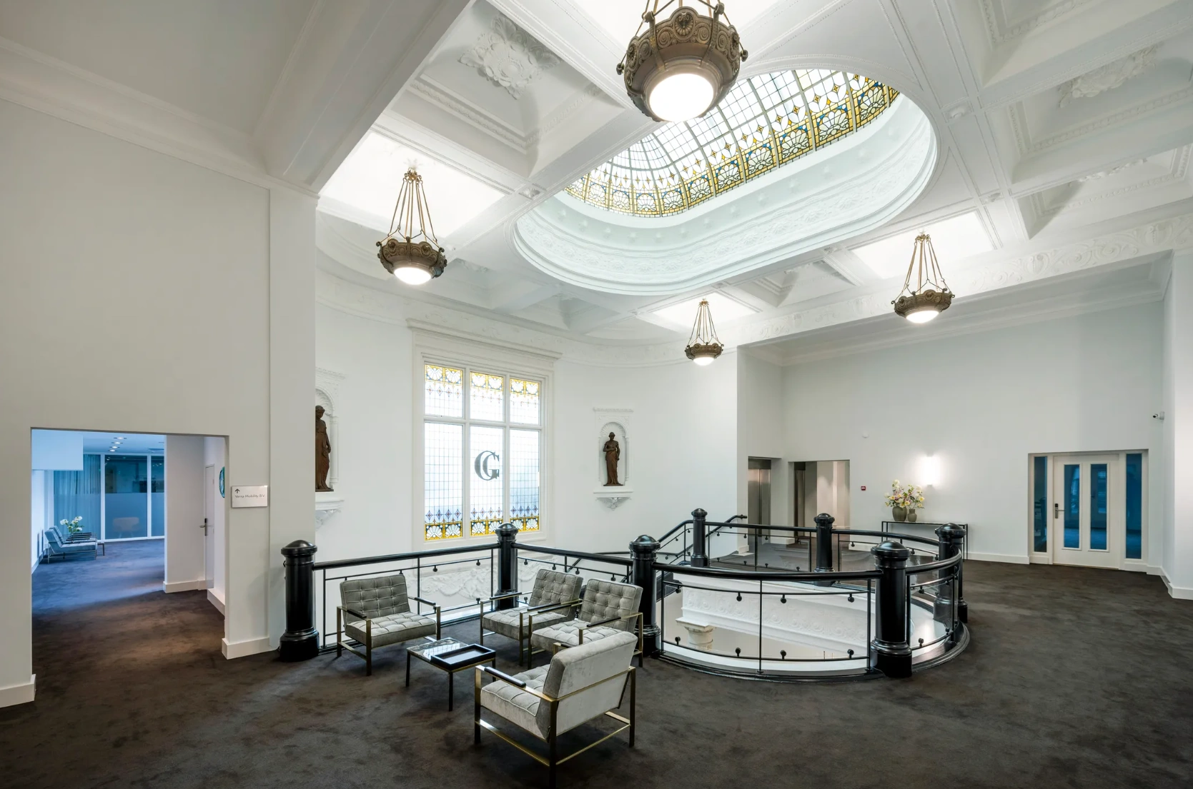 Luxe kantoorlobby aan de Paleisstraat met glazen koepelplafond, sierlijke kroonluchters en moderne zithoek.