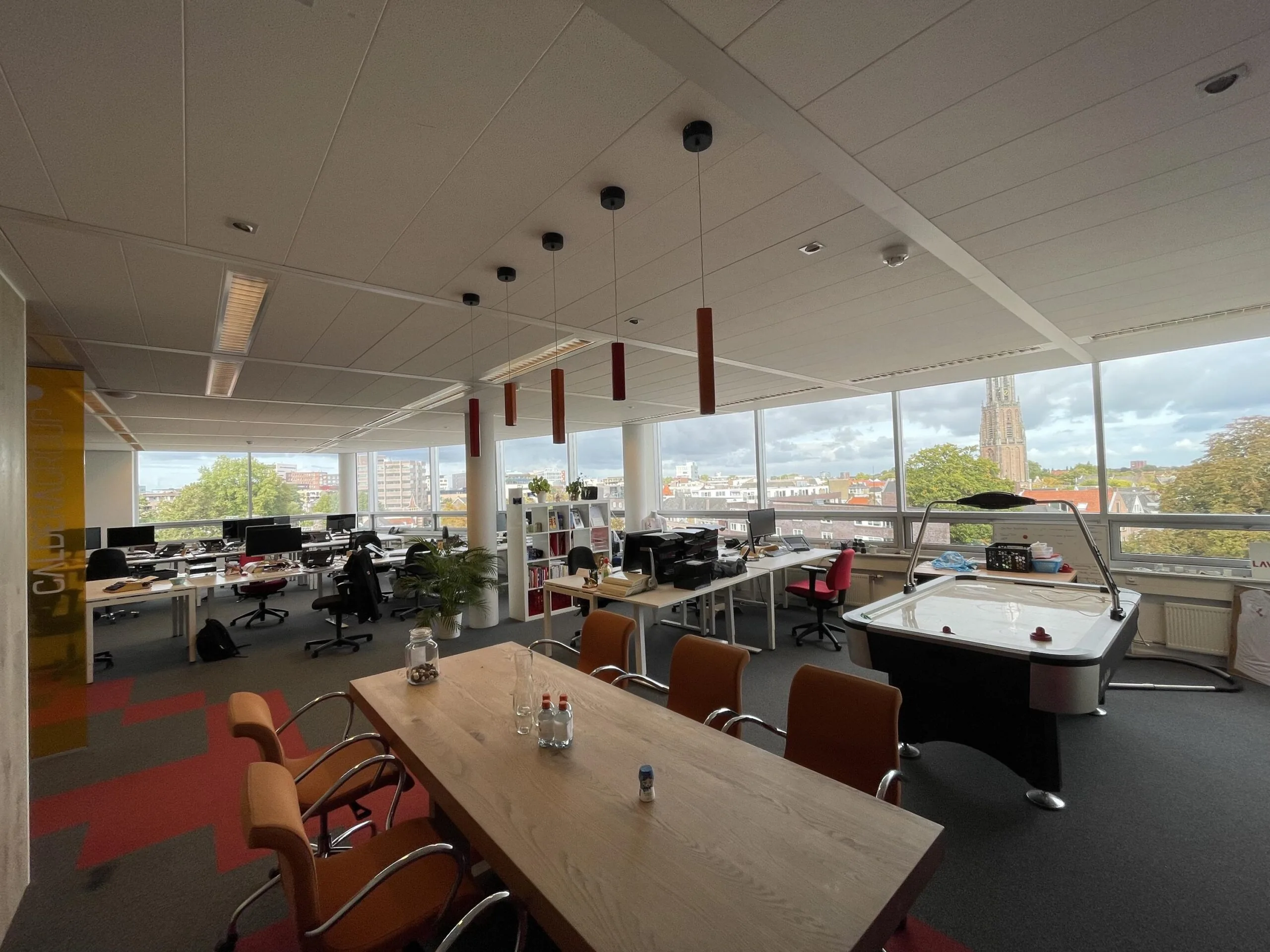 Modern kantoorinterieur aan de Arnhemseweg met werkplekken, vergadertafel en uitzicht op de stad.