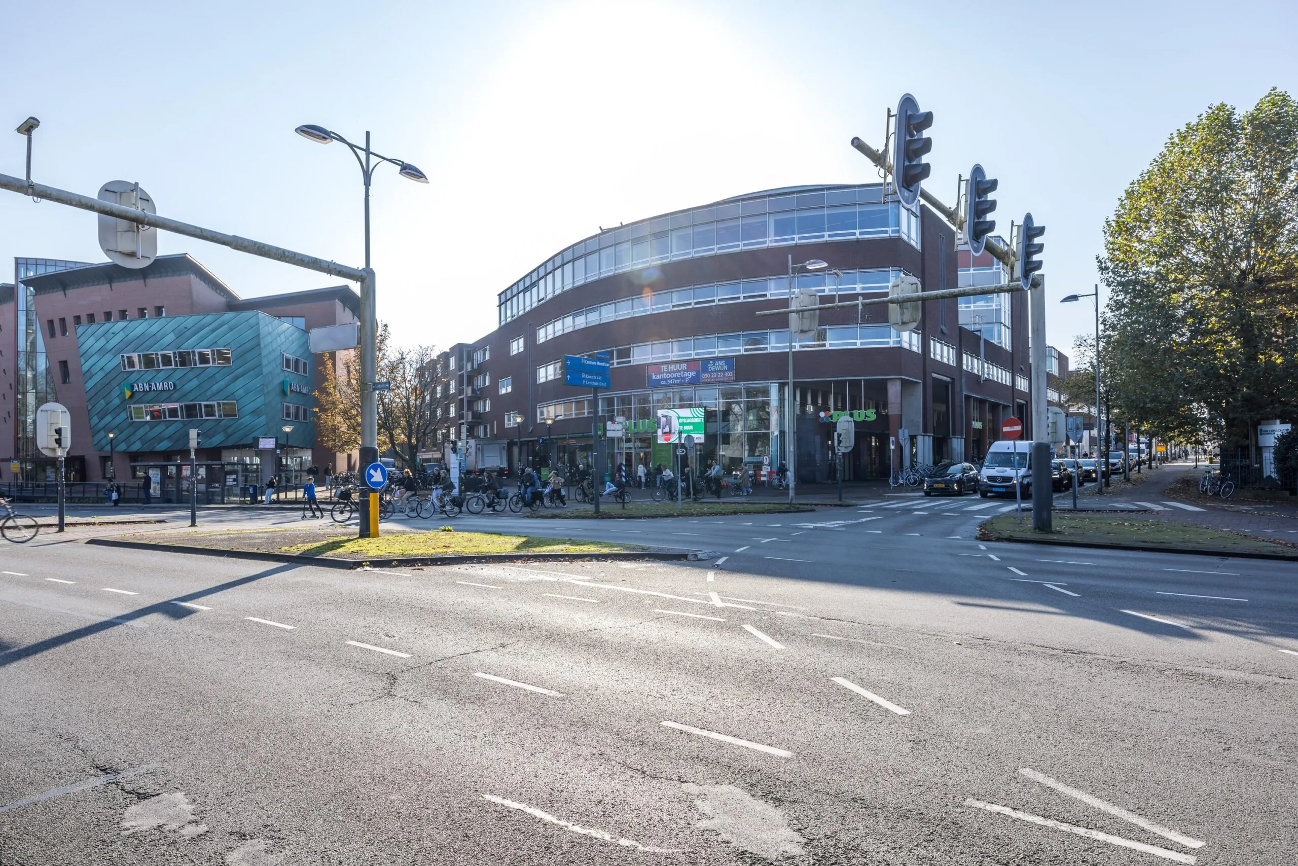Straatbeeld van de Arnhemseweg in Amersfoort met een ABN AMRO-kantoor en Plus-supermarkt op de hoek bij een druk kruispunt.