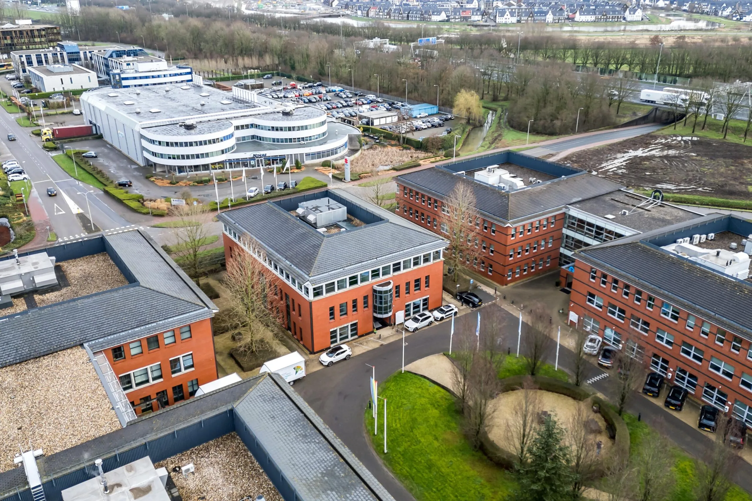 Luchtfoto van het kantorencomplex aan de Lange Dreef met meerdere rode bakstenen gebouwen en ruime parkeergelegenheid.
