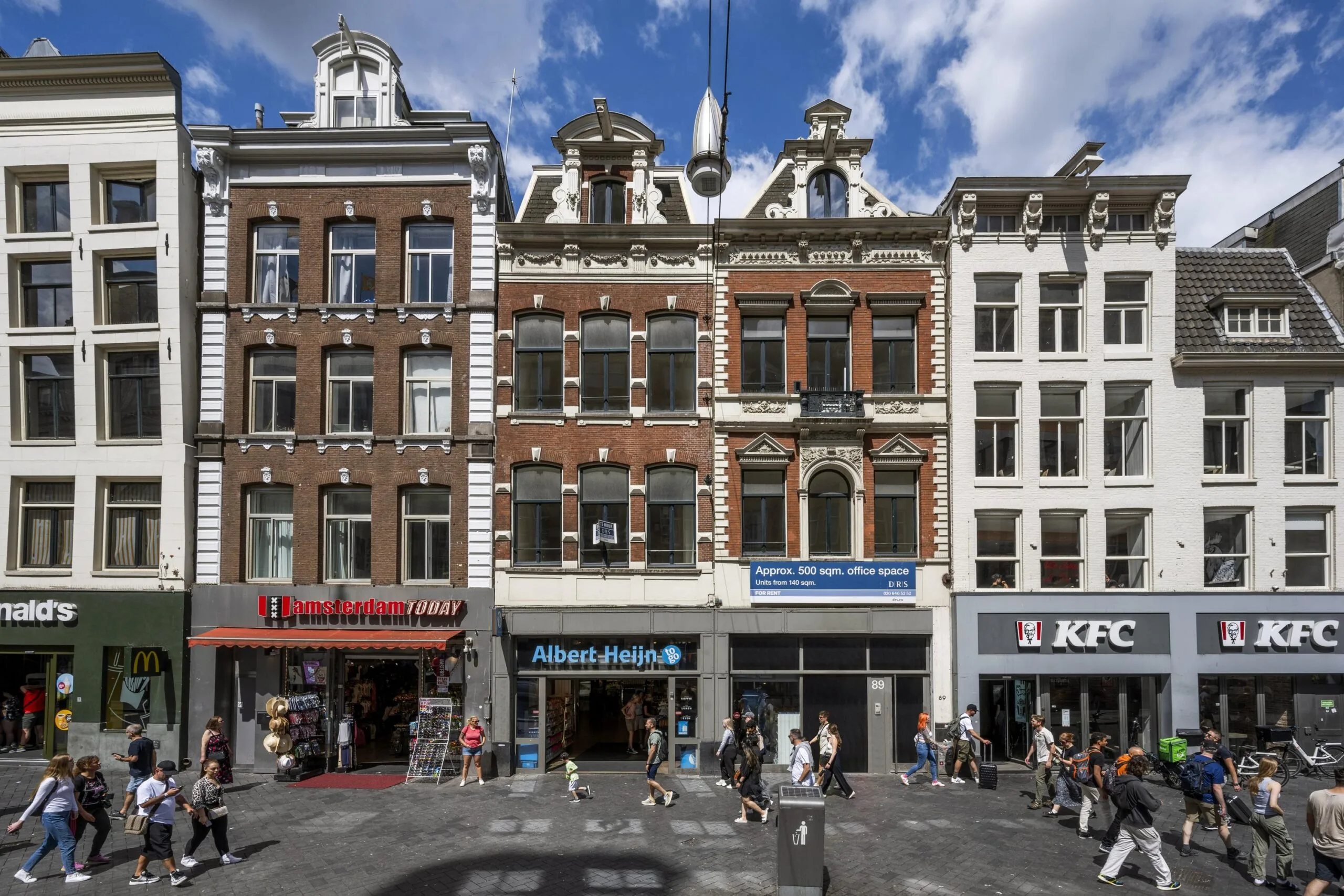 Winkelpanden aan het Damrak in Amsterdam met onder andere Albert Heijn, KFC en souvenirwinkel Amsterdam Today.