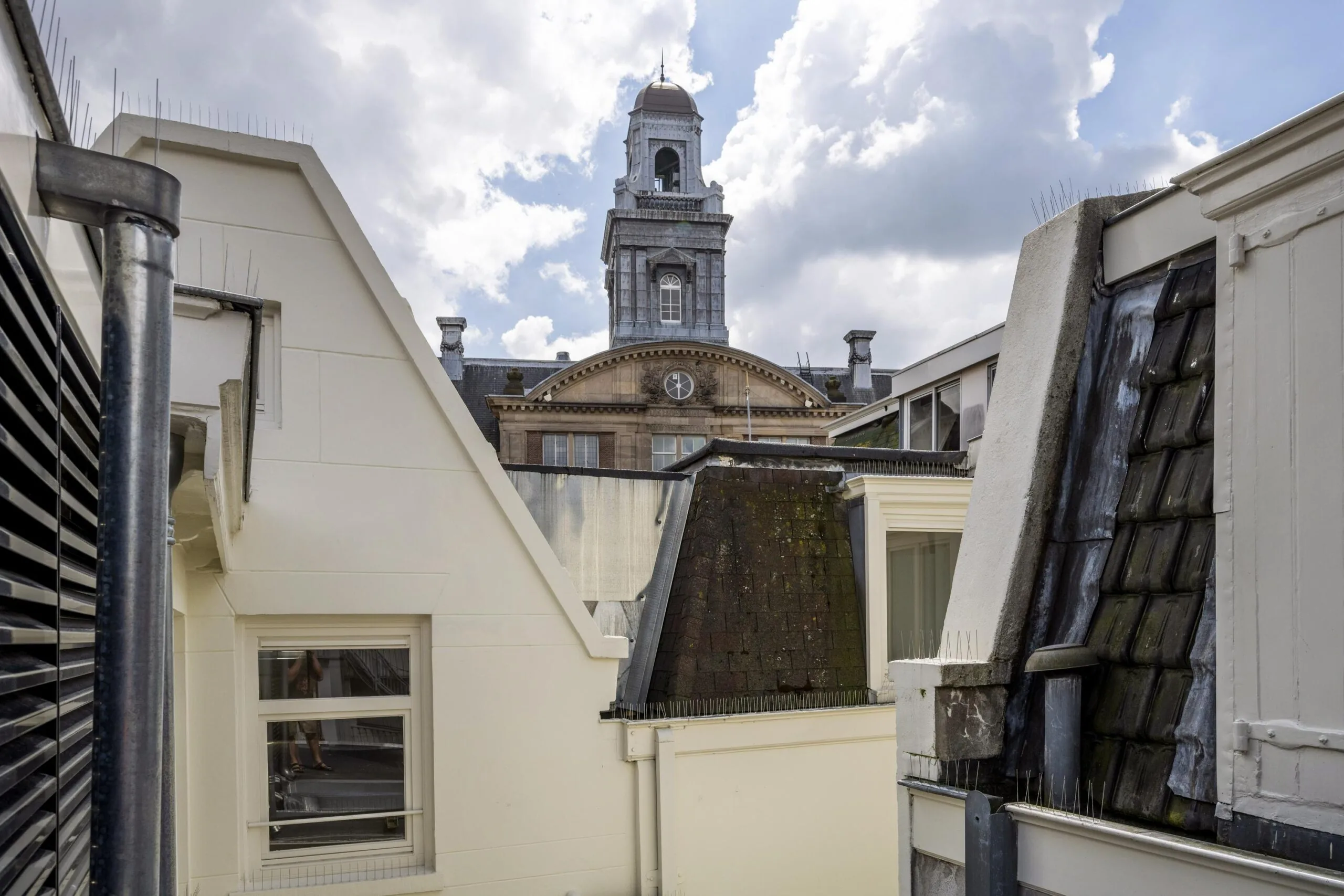 Uitzicht op het oude beursgebouw aan de Damrak in Amsterdam tussen omliggende daken.