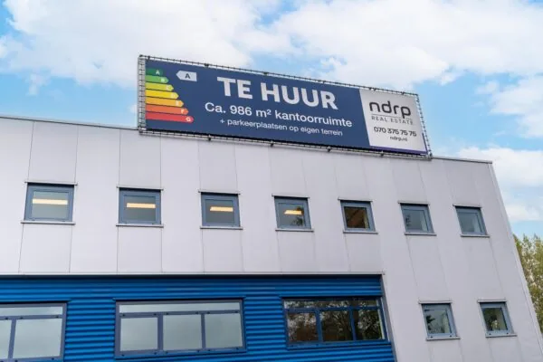 Bedrijfsgebouw aan de Zuiderweg met een groot bord waarop circa 986 m² kantoorruimte te huur wordt aangeboden.