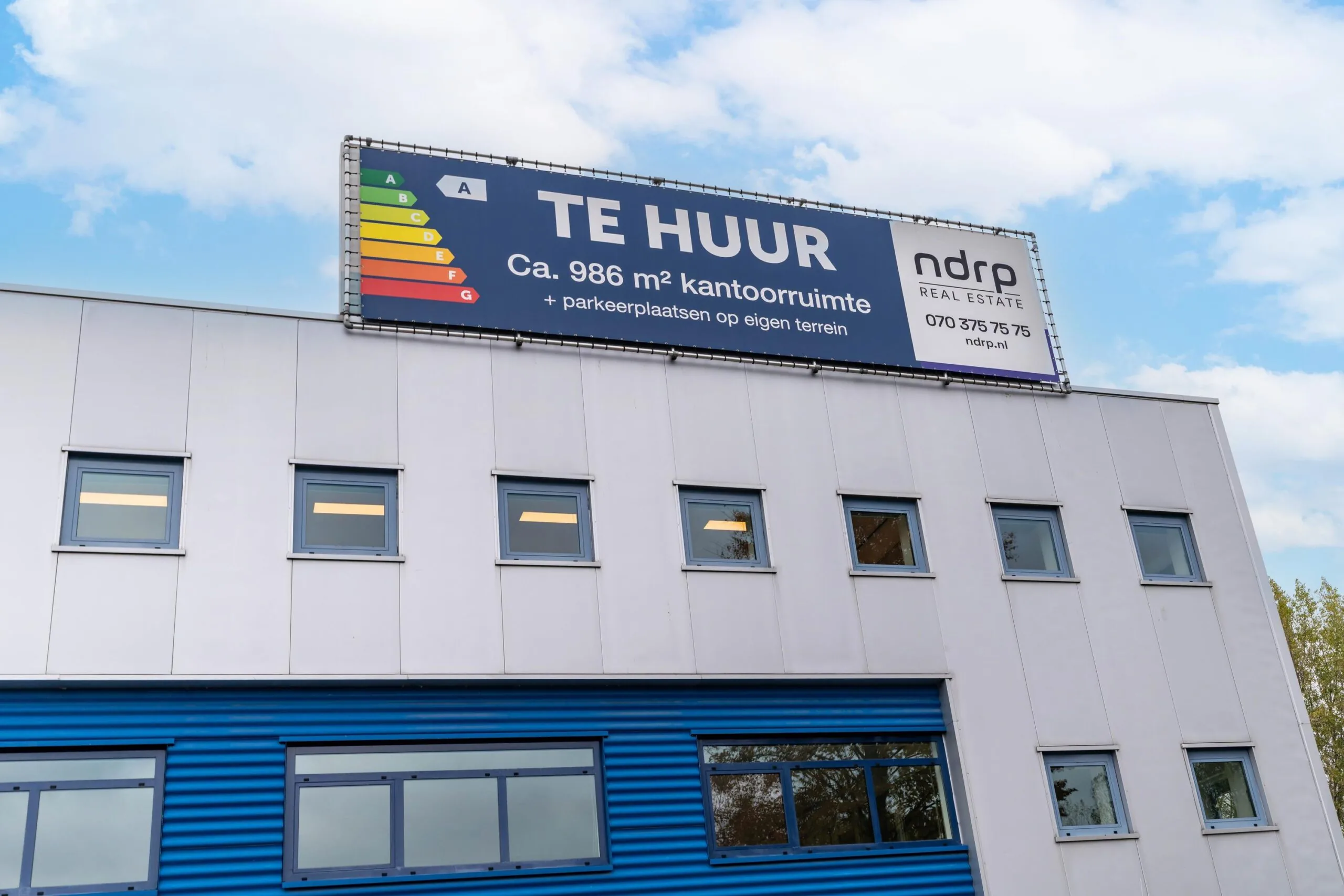 Bedrijfsgebouw aan de Zuiderweg met een groot bord waarop circa 986 m² kantoorruimte te huur wordt aangeboden.