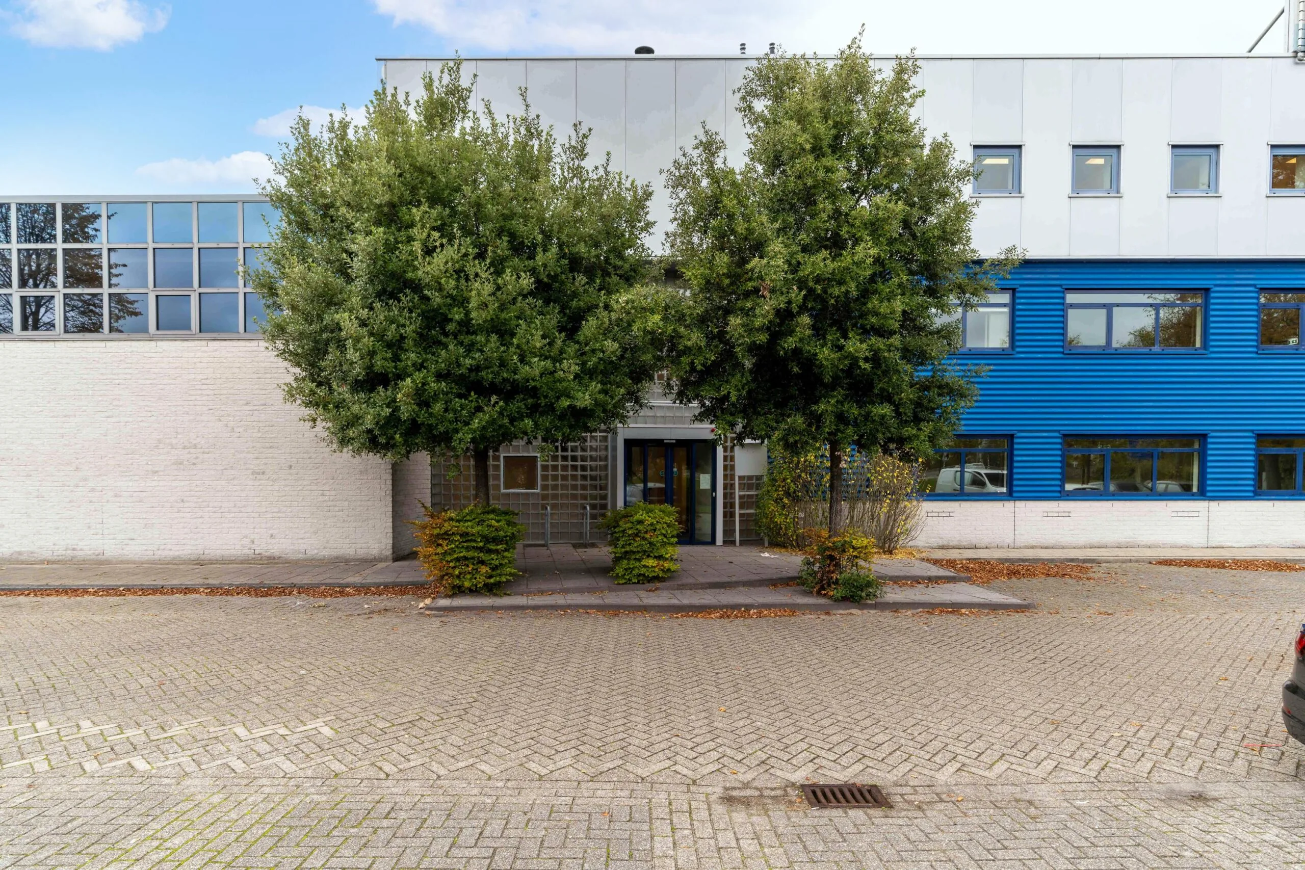 Vooraanzicht van een kantoorgebouw aan de Zuiderweg met blauwe gevel en twee grote bomen bij de entree.
