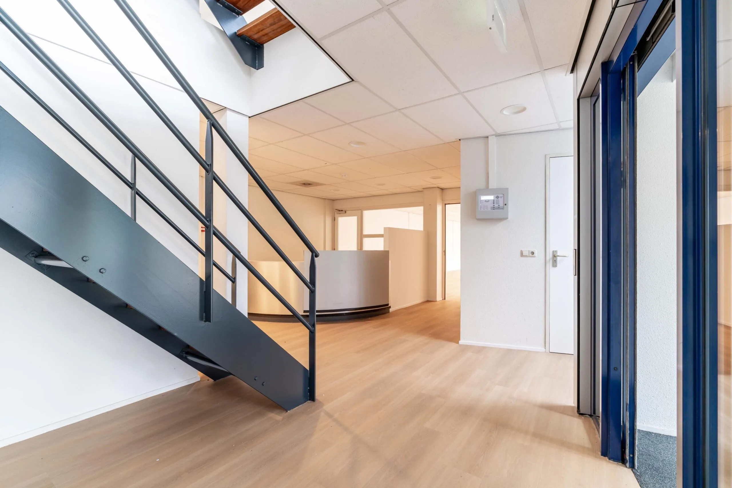 Entreehal van een modern kantoorpand aan de Zuiderweg met houten vloer, trap en balie.