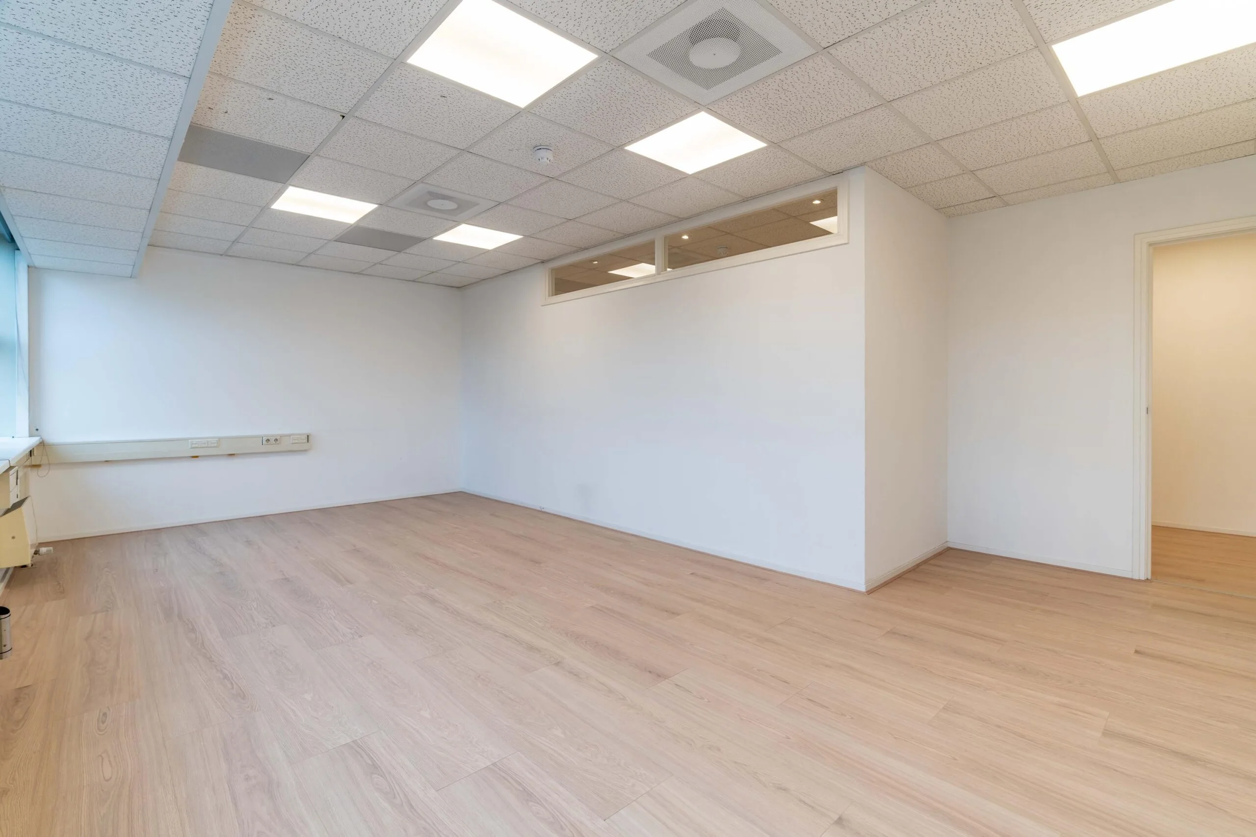 Leeg kantoorruimte aan de Zuiderweg met wit plafond, lichte houten vloer en grote ramen.