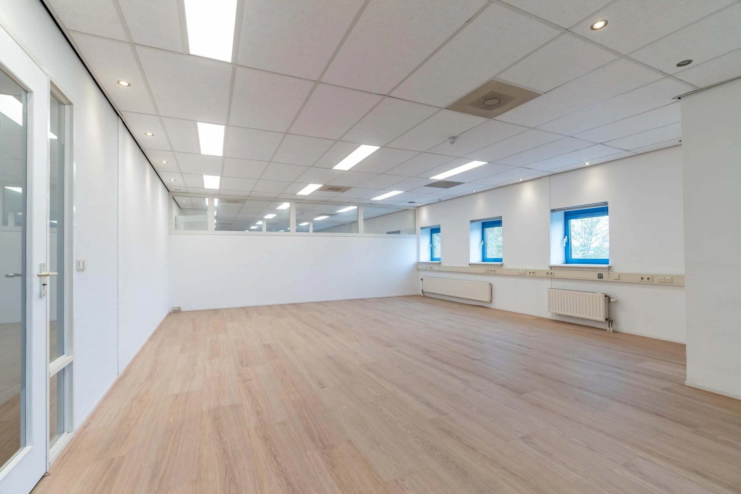Licht en ruim kantoor met houten vloer, systeemplafond en meerdere ramen aan de Zuiderweg.