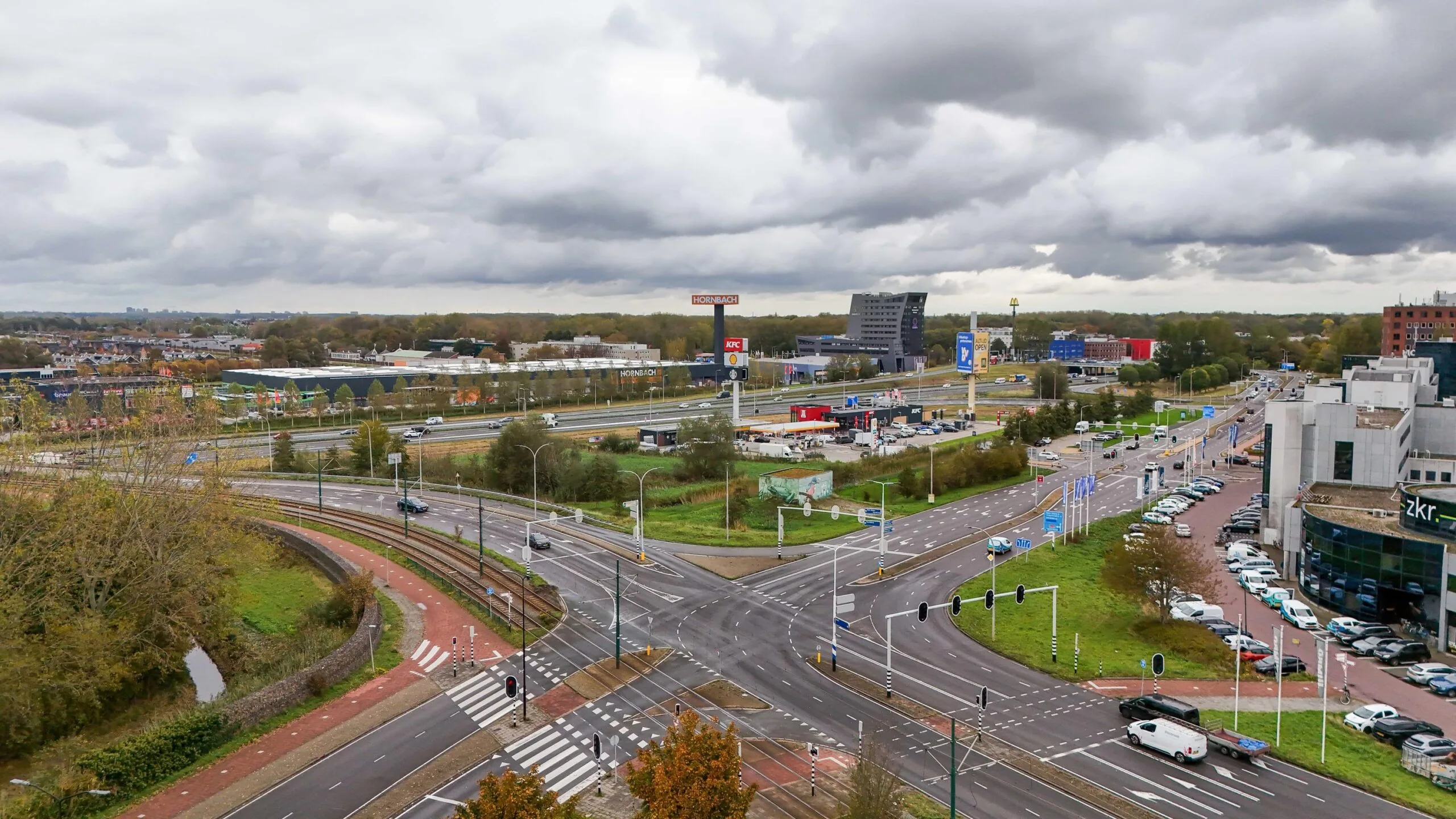 Drukke verkeersweg met kruispunt in Zuiderweg Hoorn, omringd door winkels zoals Hornbach, KFC en McDonald's onder een bewolkte lucht.