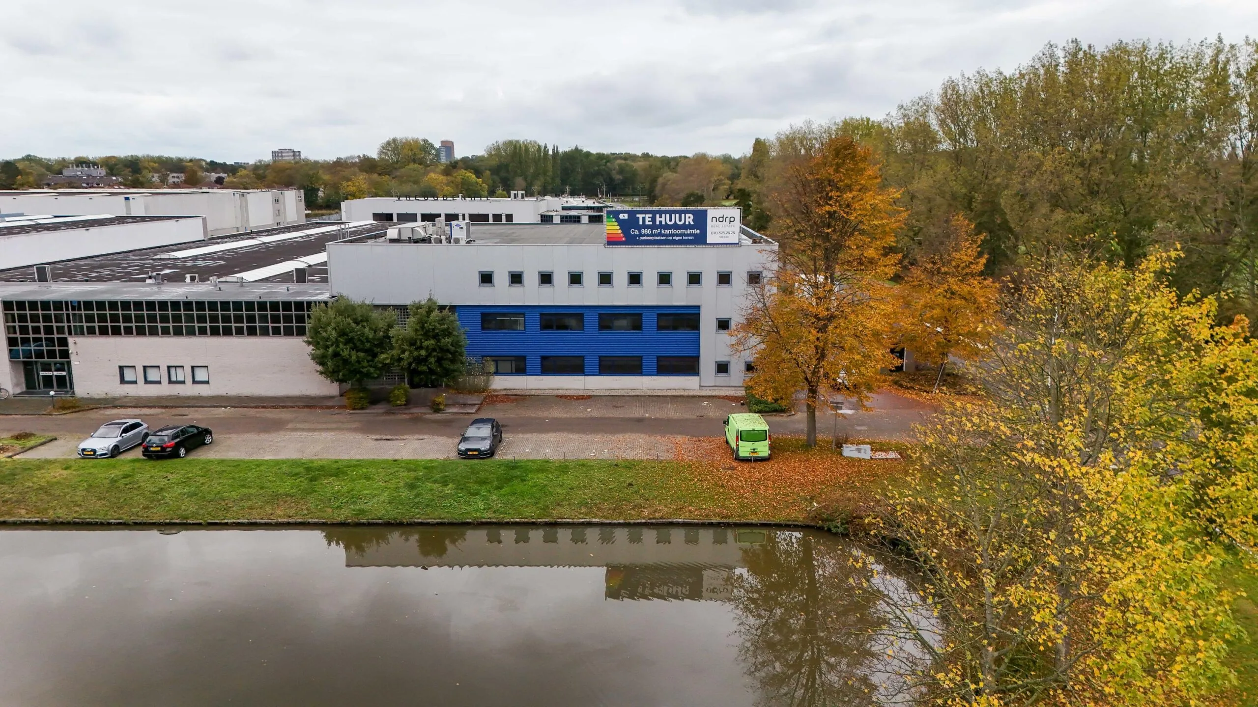 Bedrijfsgebouw aan de Zuiderweg met een 'Te Huur'-bord en een vijver op de voorgrond.