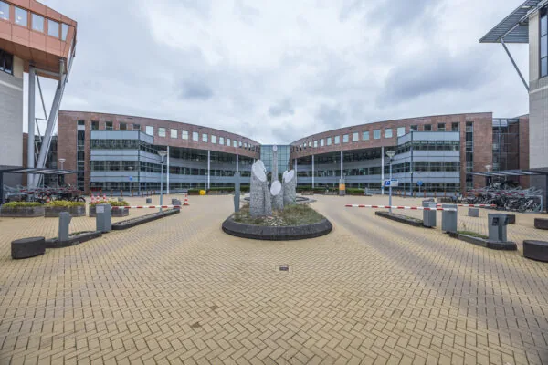 Modern office building of Olympia with a central stone sculpture and bicycle parking in front.