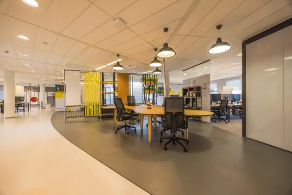Modern shared office space with round desks, ergonomic chairs, and industrial-style decor at Olympia.