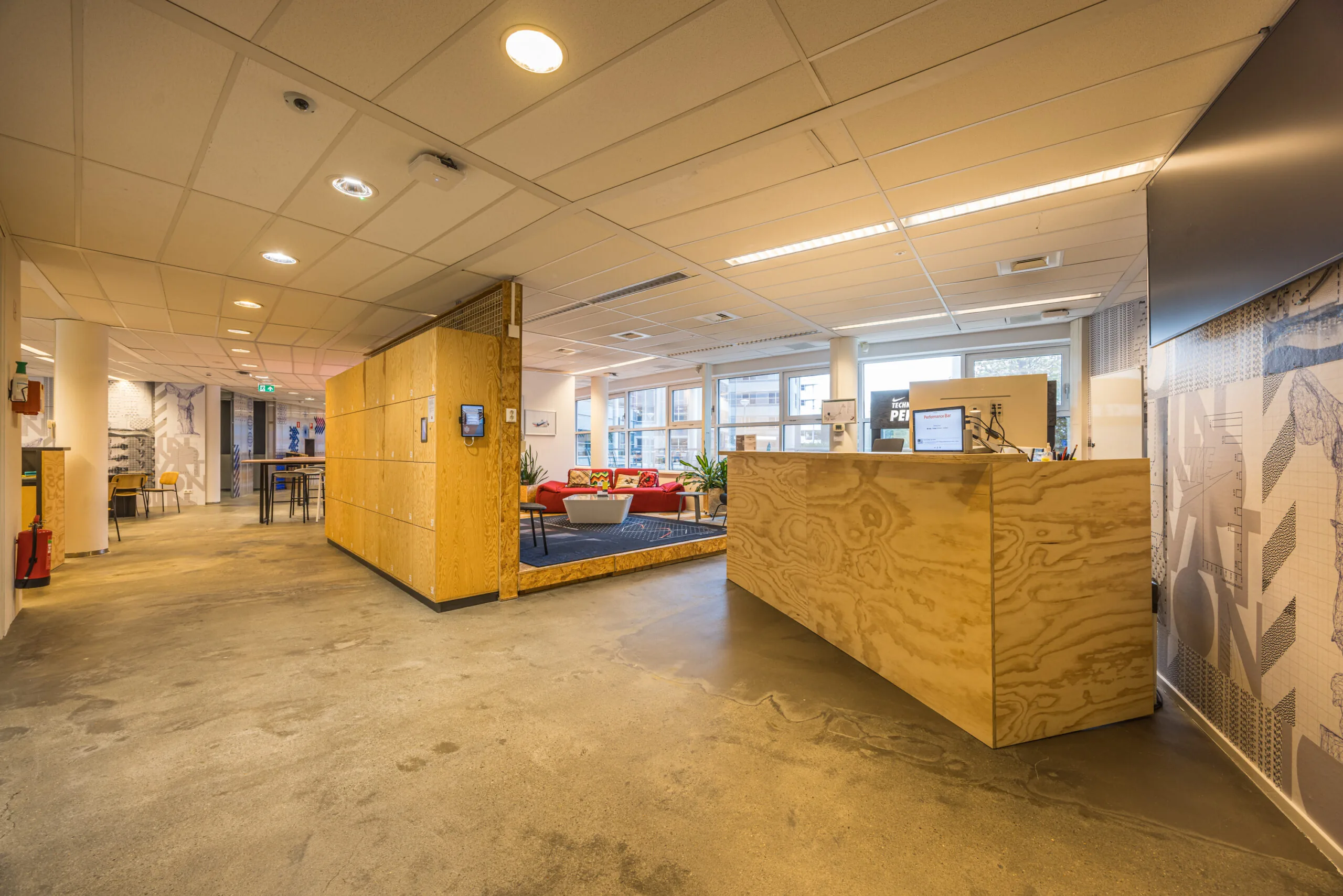 Modern office reception area of Olympia with wooden furniture, open seating space, and bright natural lighting.