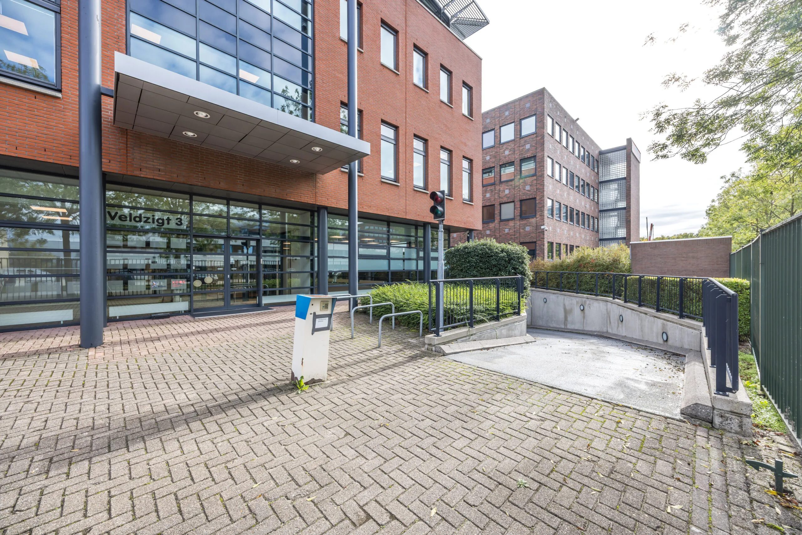 Entrance of the Veldzigt 3 office building with adjacent underground parking ramp.