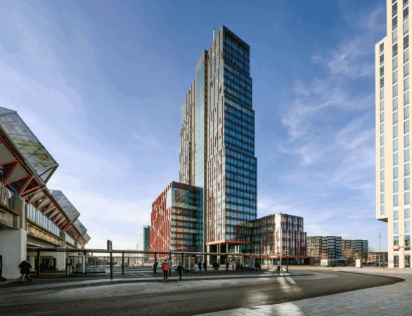 Modern high-rise buildings on P.J. Oudweg in Almere, with a bus stop and pedestrians in the foreground.