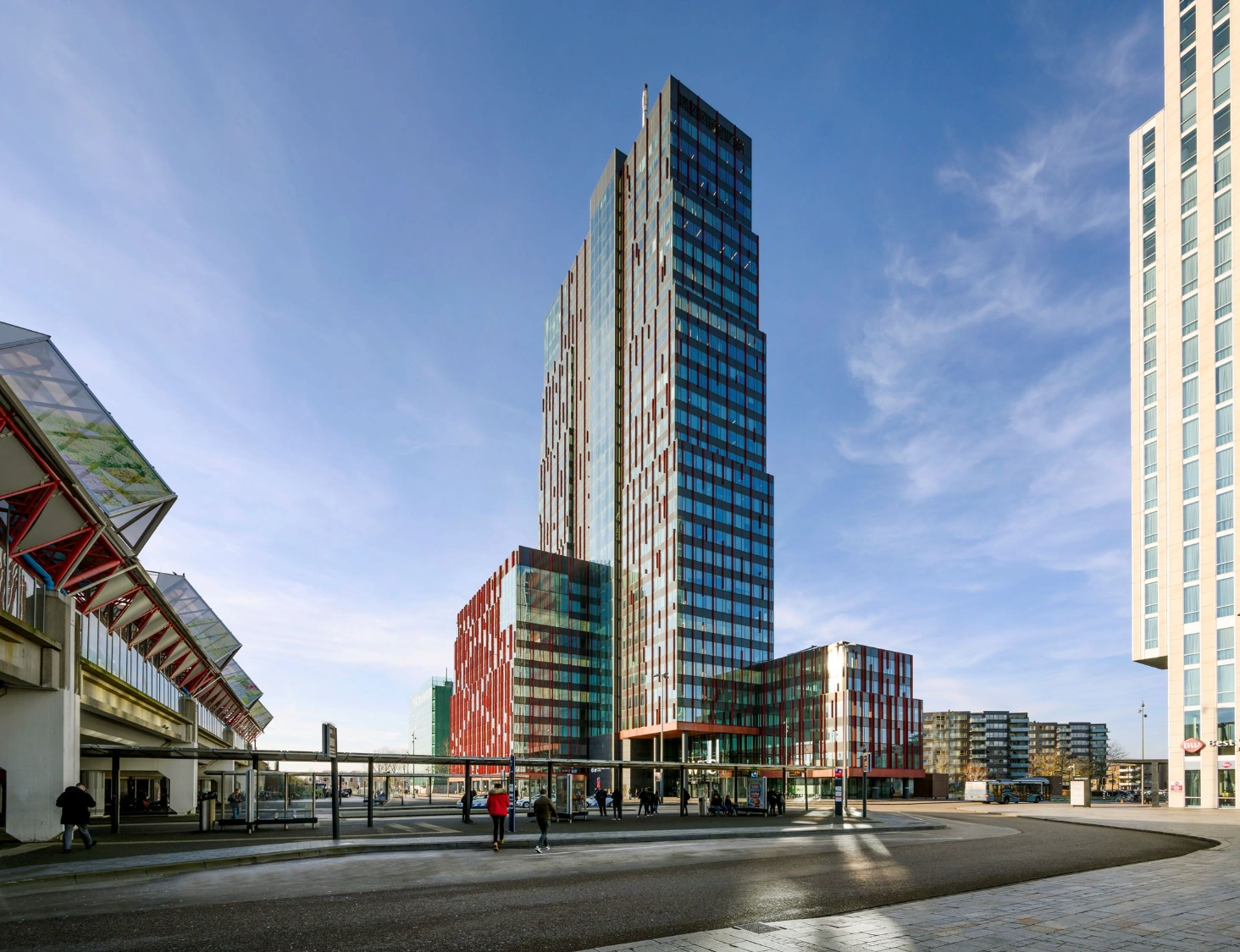 Modern high-rise buildings on P.J. Oudweg in Almere, with a bus stop and pedestrians in the foreground.