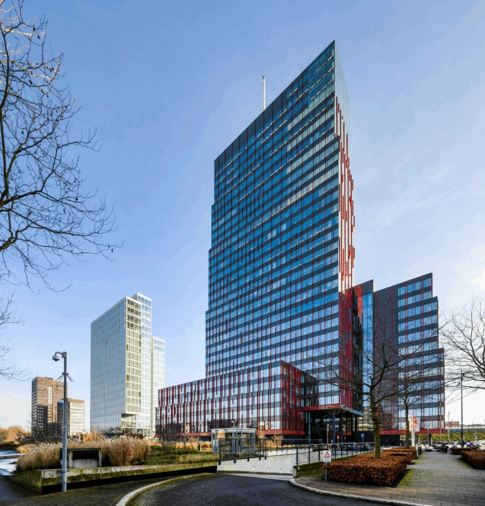 Modern office buildings along P.J. Oudweg in Almere, including a tall red-and-blue glass skyscraper.