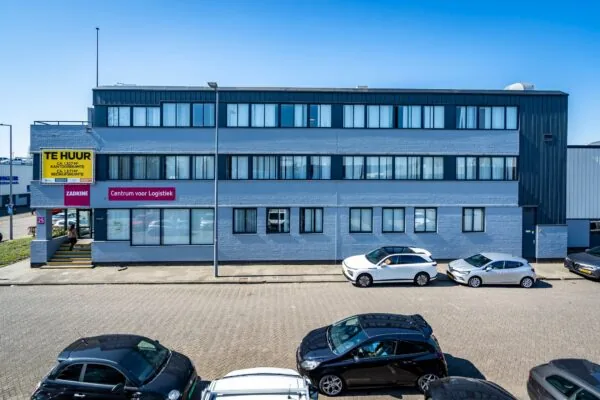 Modern three-story office and logistics building on Aluminiumstraat with cars parked in front and a "For Rent" sign displayed.
