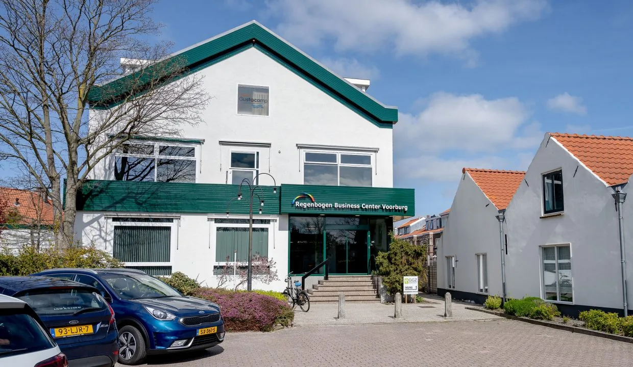 Front view of Regenbogen Business Center Voorburg with parked cars and a clear blue sky.