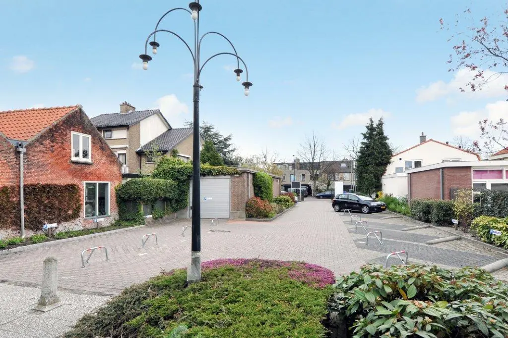 Residential parking area on Oosteinde street with surrounding houses and greenery under a clear blue sky.