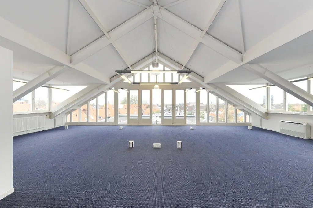 Spacious attic office space with high vaulted ceiling and large windows at Oosteinde.