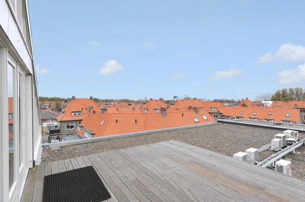 Rooftop terrace with wooden decking overlooking red-tiled roofs in the Oosteinde neighborhood.