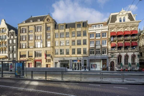 Street view of historic buildings along Rokin in Amsterdam, featuring a tram stop and shops at ground level.