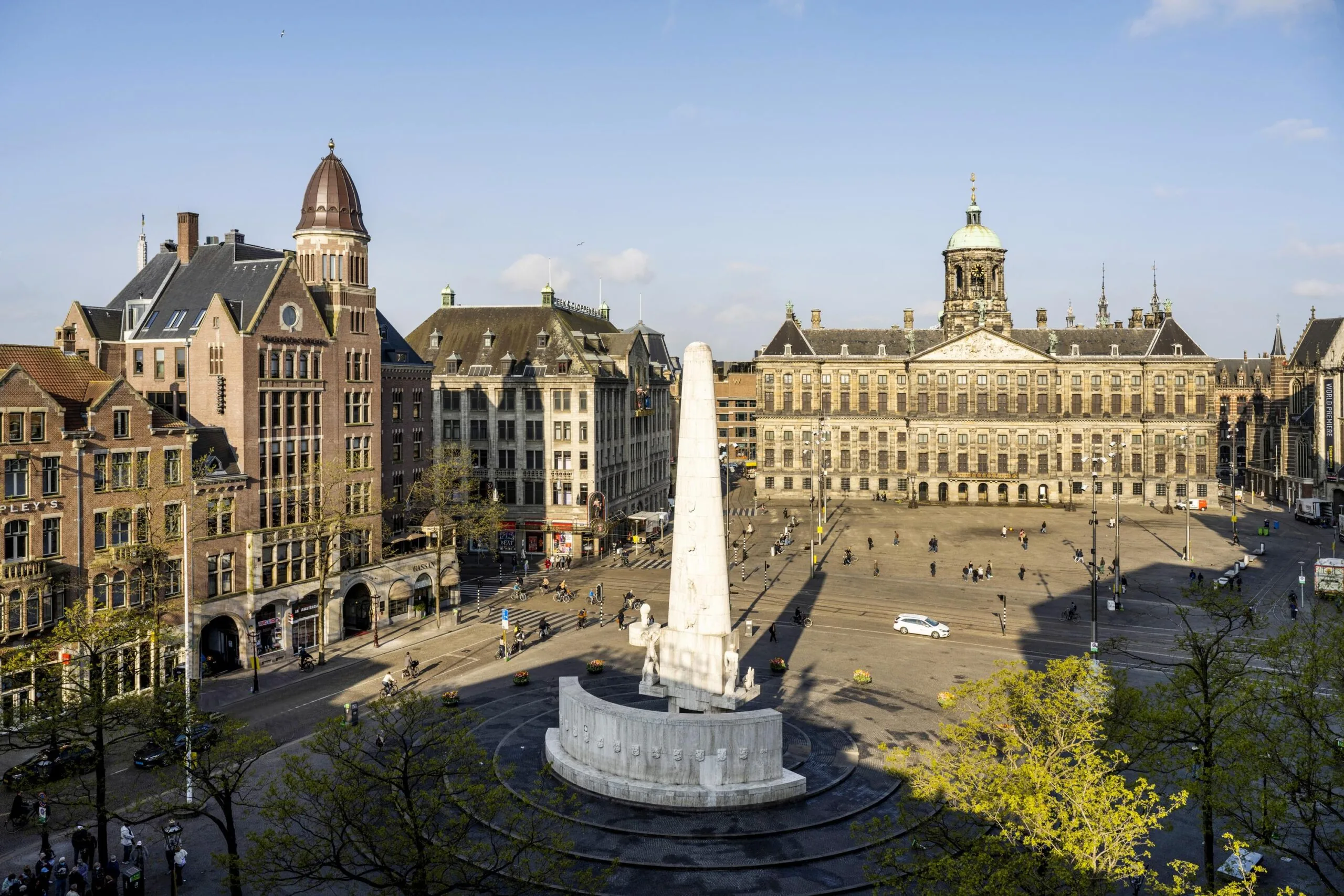 View of Dam Square in Amsterdam with the National Monument and Royal Palace on a sunny day.