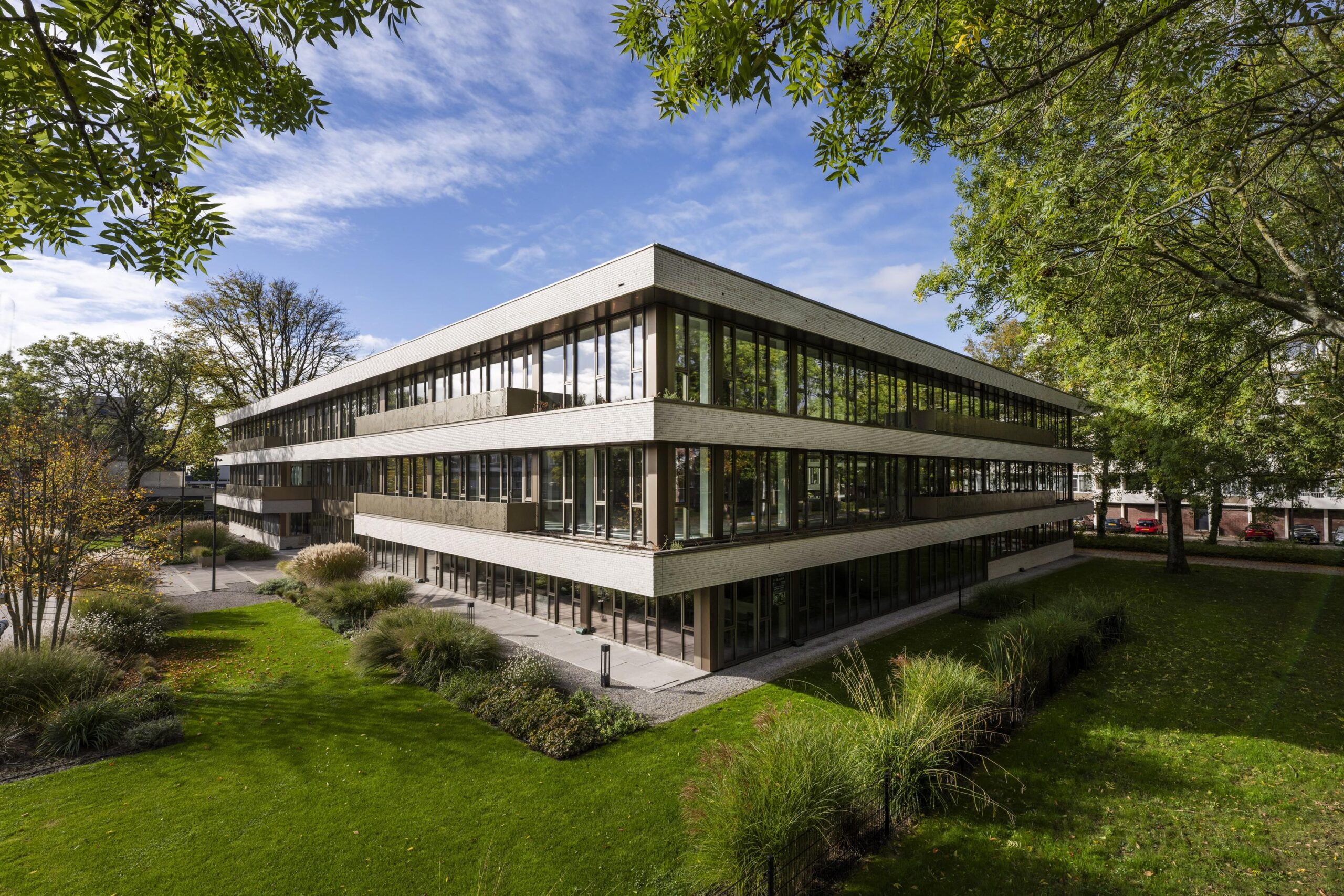 Modern three-story office building "Walborg" surrounded by greenery and trees under a partly cloudy sky.