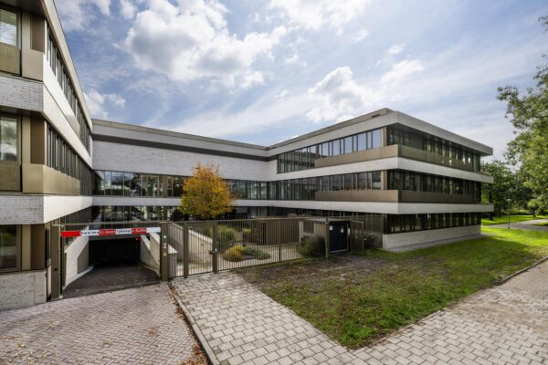 Modern office building "Walborg" with large glass windows and a gated underground parking entrance.