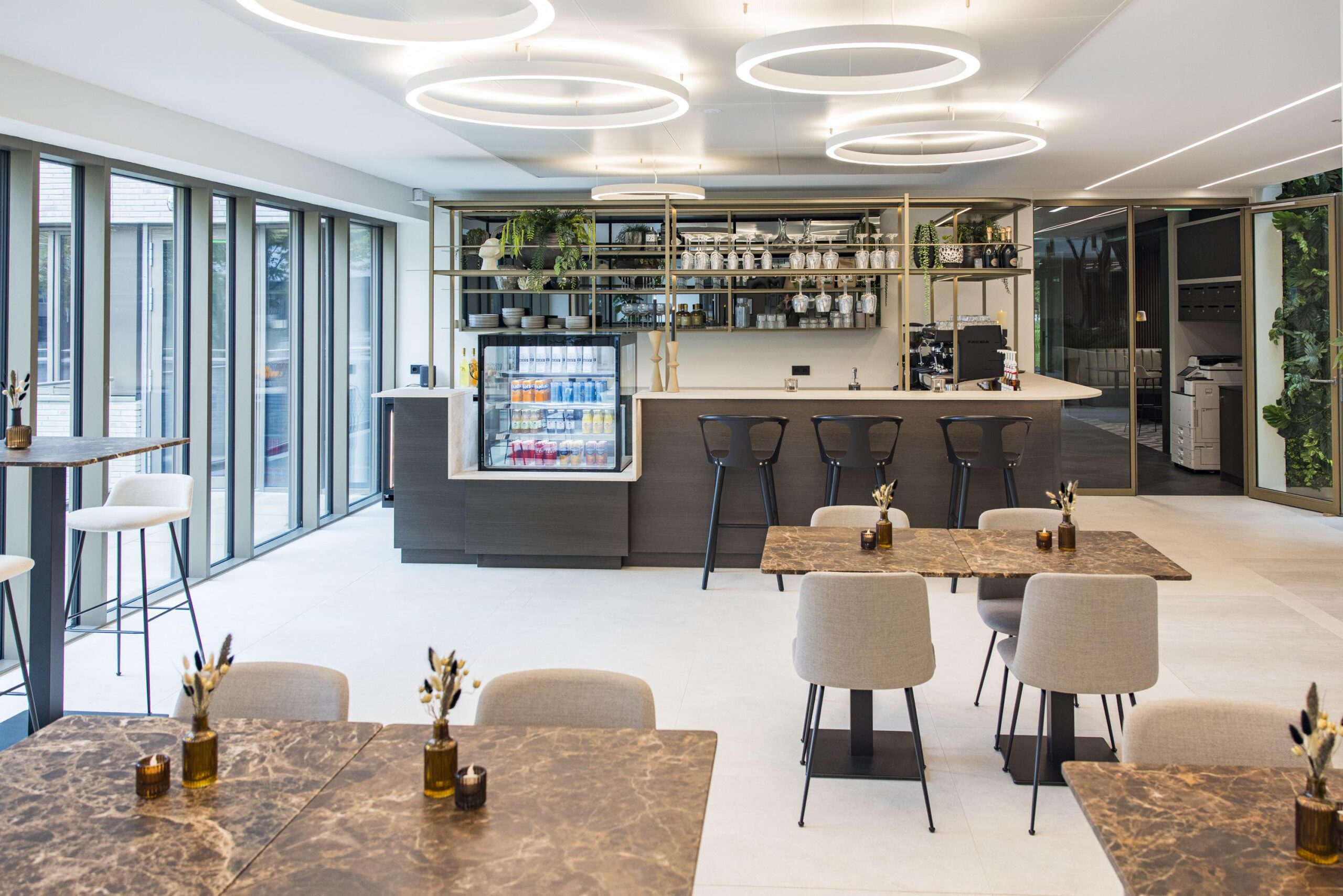 Modern café interior at Walborg with marble tables, a sleek bar area, and hanging circular light fixtures.