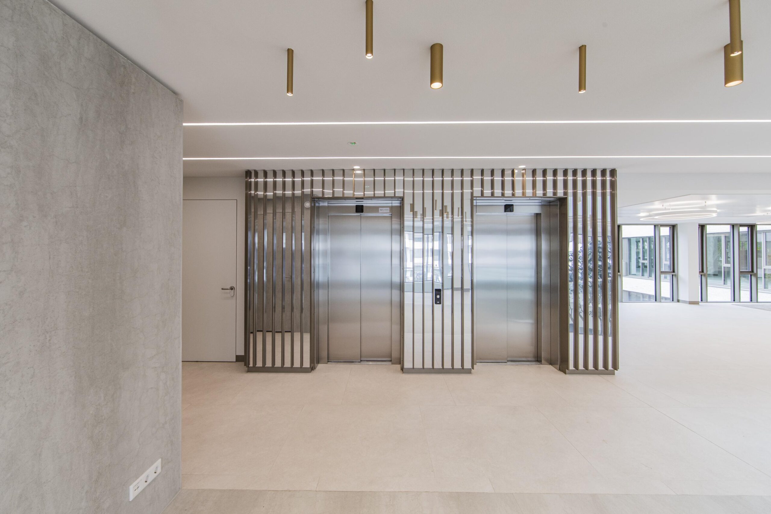 Modern lobby area with two stainless steel elevators and vertical metallic panel accents at Walborg.