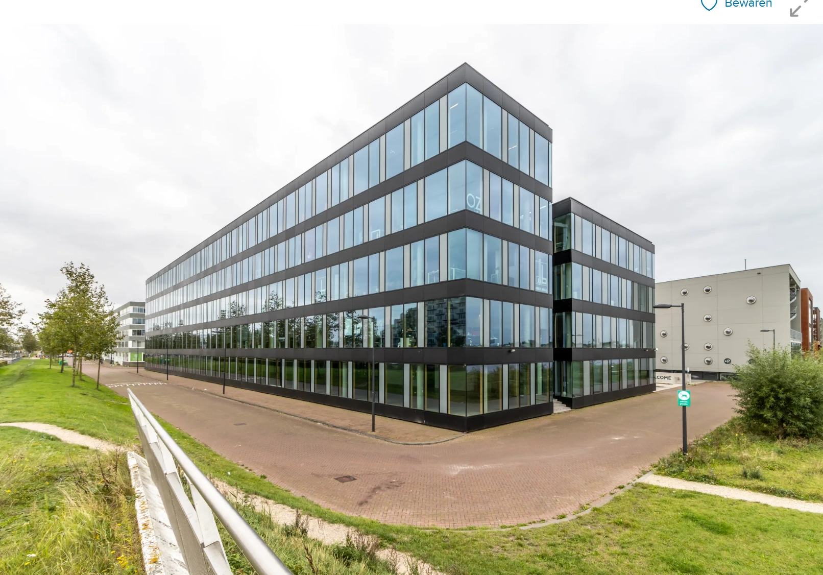 Modern glass office building on Pedro de Medinalaan in Amsterdam, viewed from the street corner.