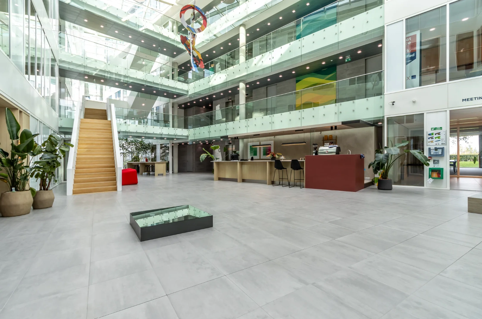 Modern atrium of the Pedro de Medinalaan office building with open staircases, glass balconies, a reception area, and contemporary art installation.