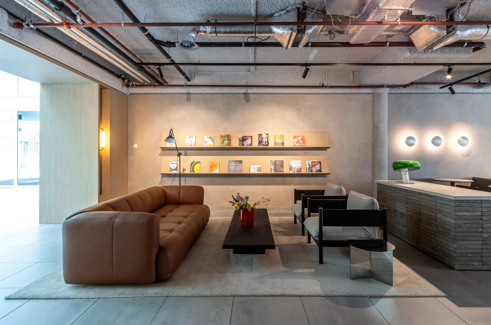 Modern lounge area on Pedro de Medinalaan with a brown leather sofa, minimalist furniture, and wall-mounted magazine display.