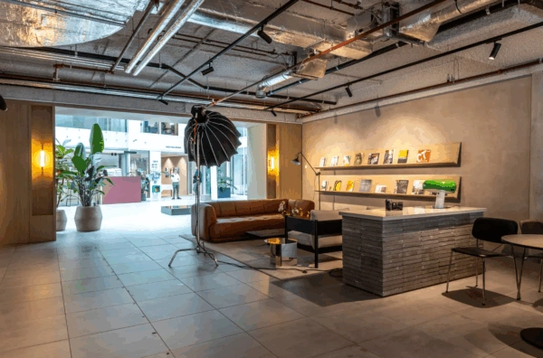 Modern lounge area at Pedro de Medinalaan with a brown sofa, magazine display, and industrial ceiling design.