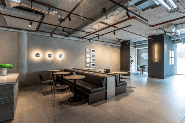 Modern seating area with round tables and black booths in the Pedro de Medinalaan office interior.