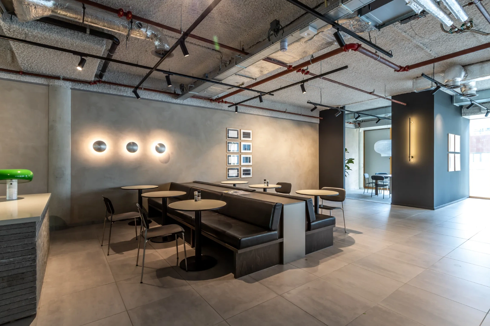 Modern seating area with round tables and black booths in the Pedro de Medinalaan office interior.